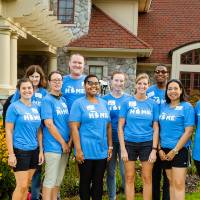 Alumni pose in front of the Alumni House